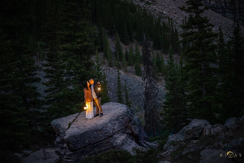 Couple Kissing While Holding a Night Lamp on Top of a Rock Formation